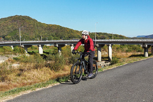 小田川沿いを自転車で走る男性
