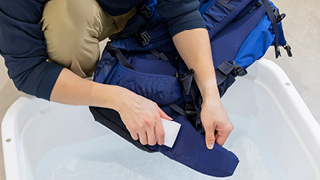 バックパックの汚れたウエストベルト部分をスポンジでこすっている