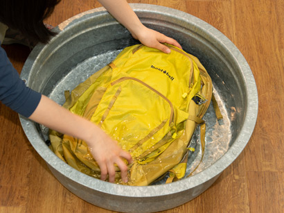 リュックサックを水槽に入れて洗っている写真。